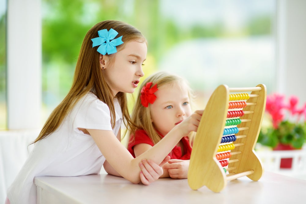 Two cute little girls engaging in kindergarten math activities at home